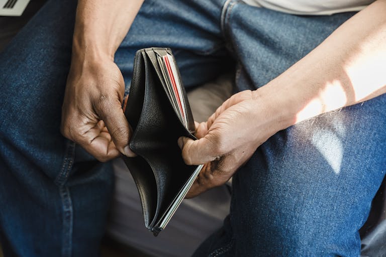 Close-up of a man holding an empty wallet, symbolizing financial crisis and hardship.